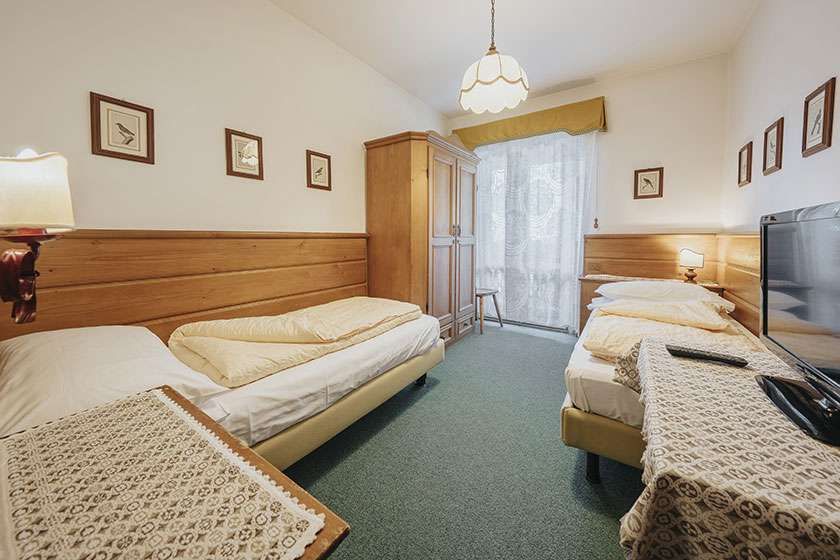 Una camera d'albergo con due letti e una tv a schermo piatto.
