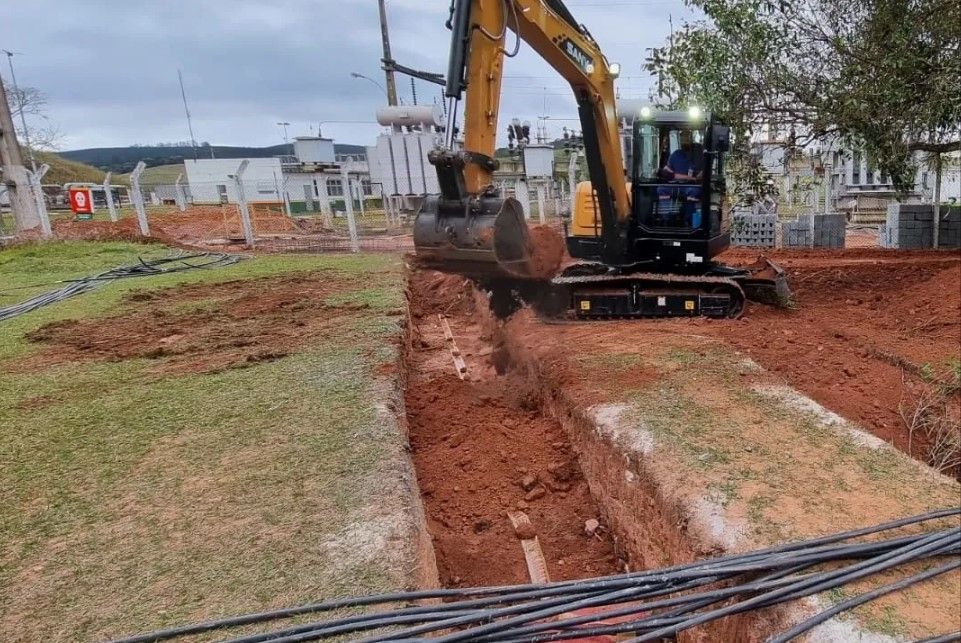Uma escavadeira está cavando um buraco no chão.
