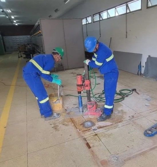Dois homens usando capacetes estão trabalhando em uma máquina