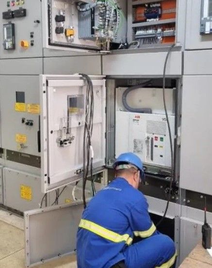Um homem de uniforme azul está trabalhando em uma caixa elétrica