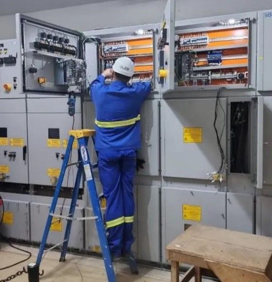 Um homem em pé em uma escada trabalhando em painéis elétricos