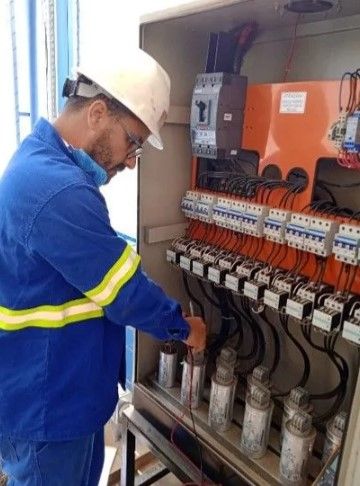 Um homem com capacete está trabalhando em uma caixa elétrica.