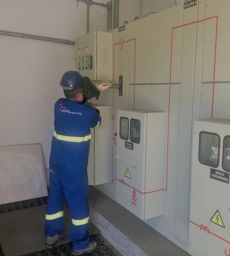 Um homem de macacão azul está trabalhando em um painel elétrico
