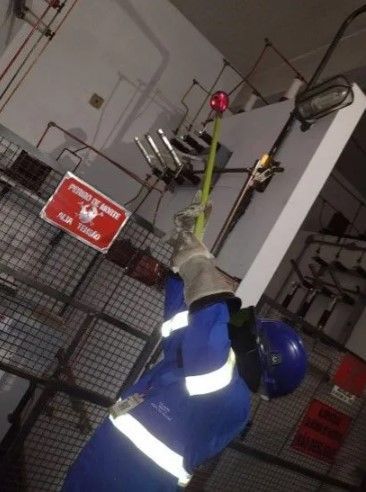 Um homem com um traje de segurança azul está segurando uma corda em uma sala.