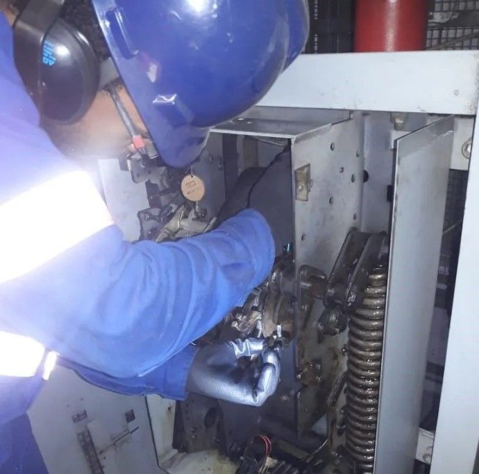 Um homem usando um capacete azul está trabalhando em uma máquina