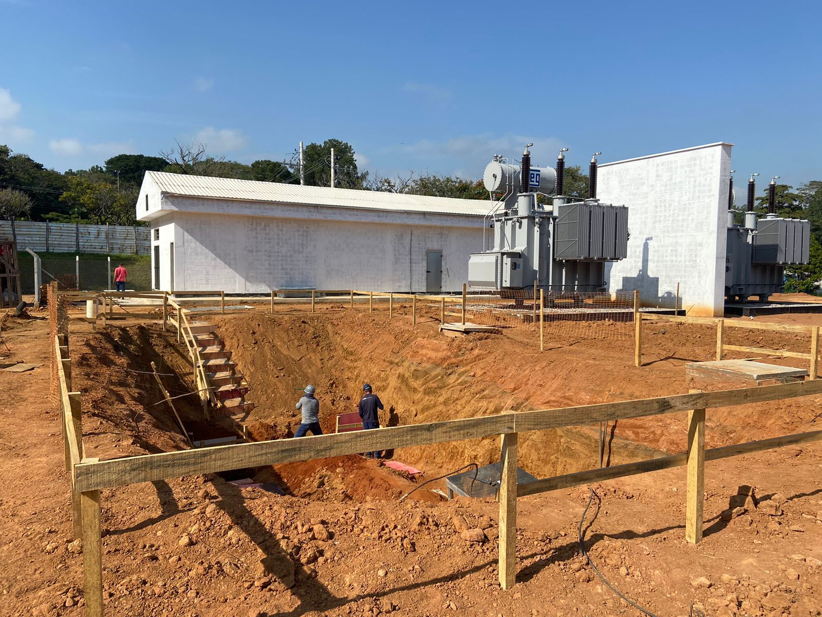 Um canteiro de obras com uma cerca de madeira e um prédio ao fundo.