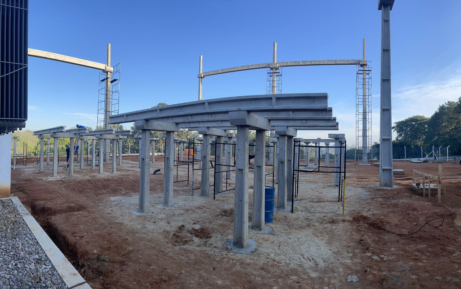 Uma grande estrutura de metal está sendo construída em um campo de terra.