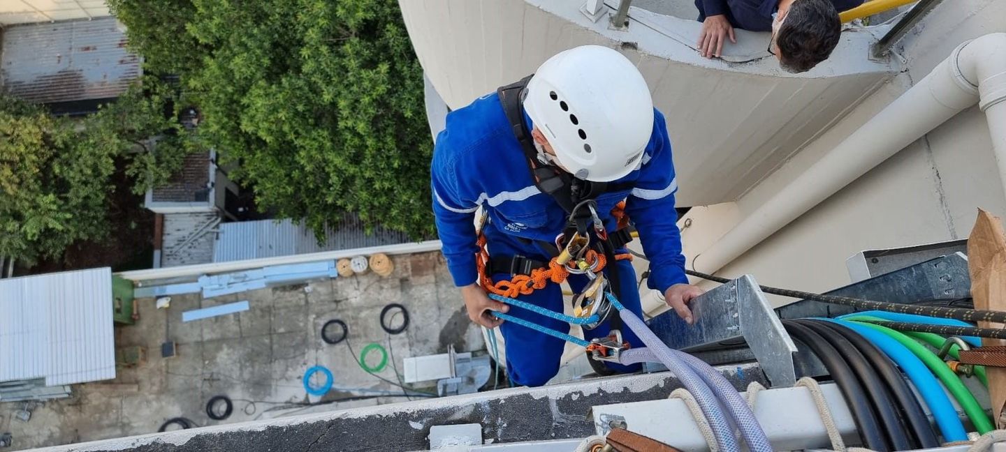 Um homem está trabalhando em um cano na lateral de um prédio.