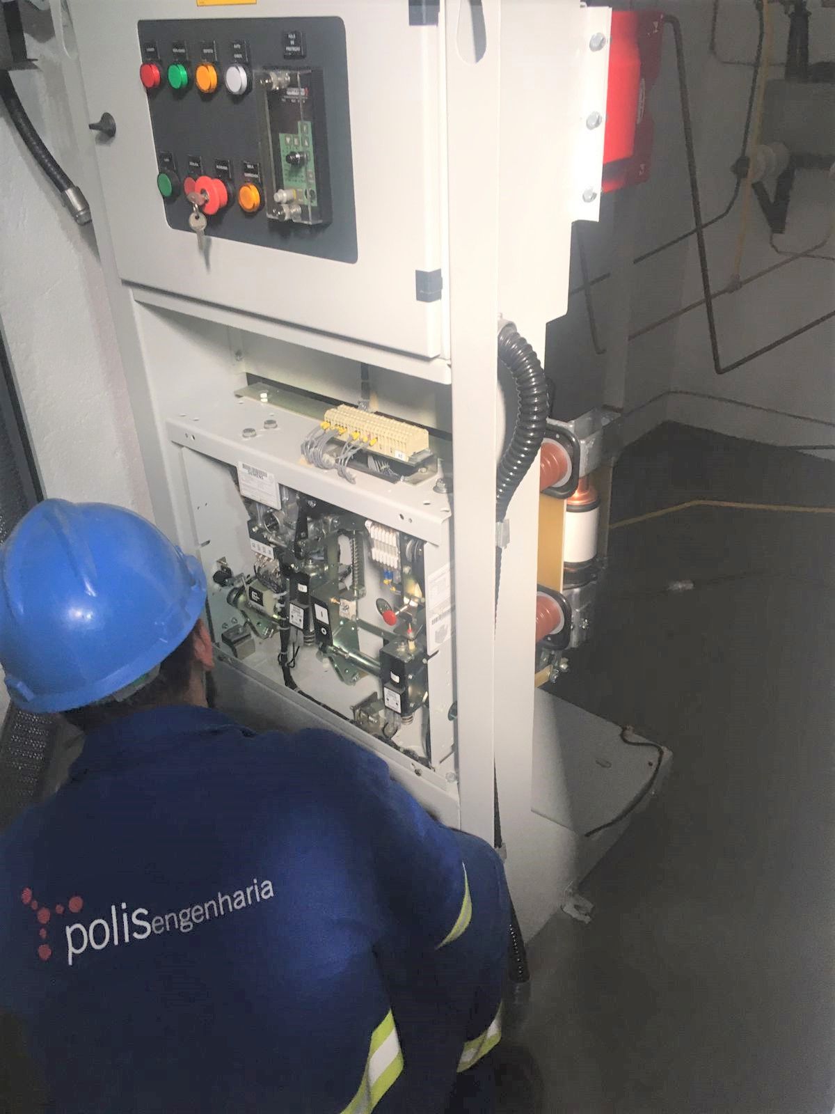 Um homem usando um capacete azul está trabalhando em uma máquina.