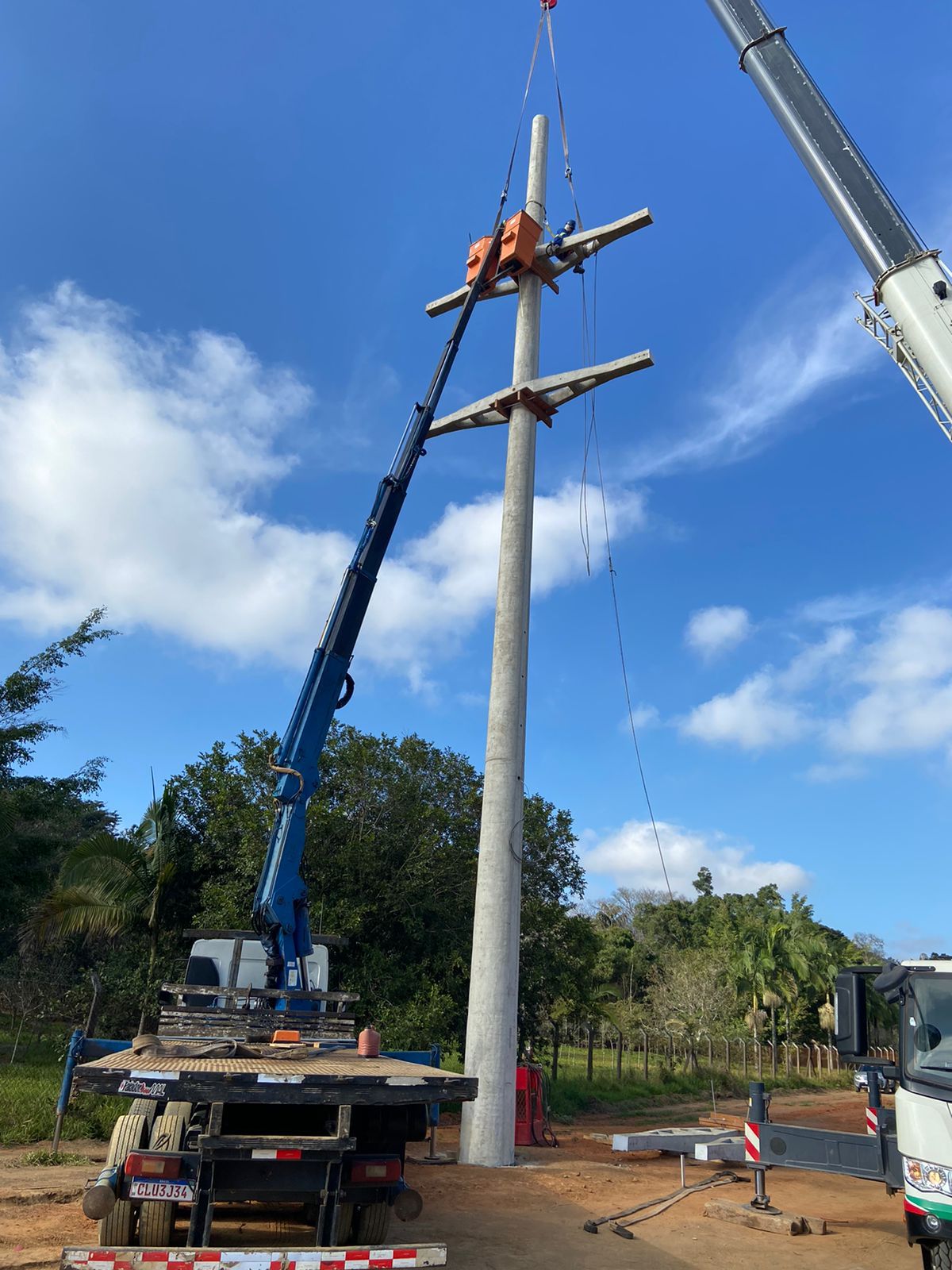 Um guindaste está levantando um poste telefônico em um campo.