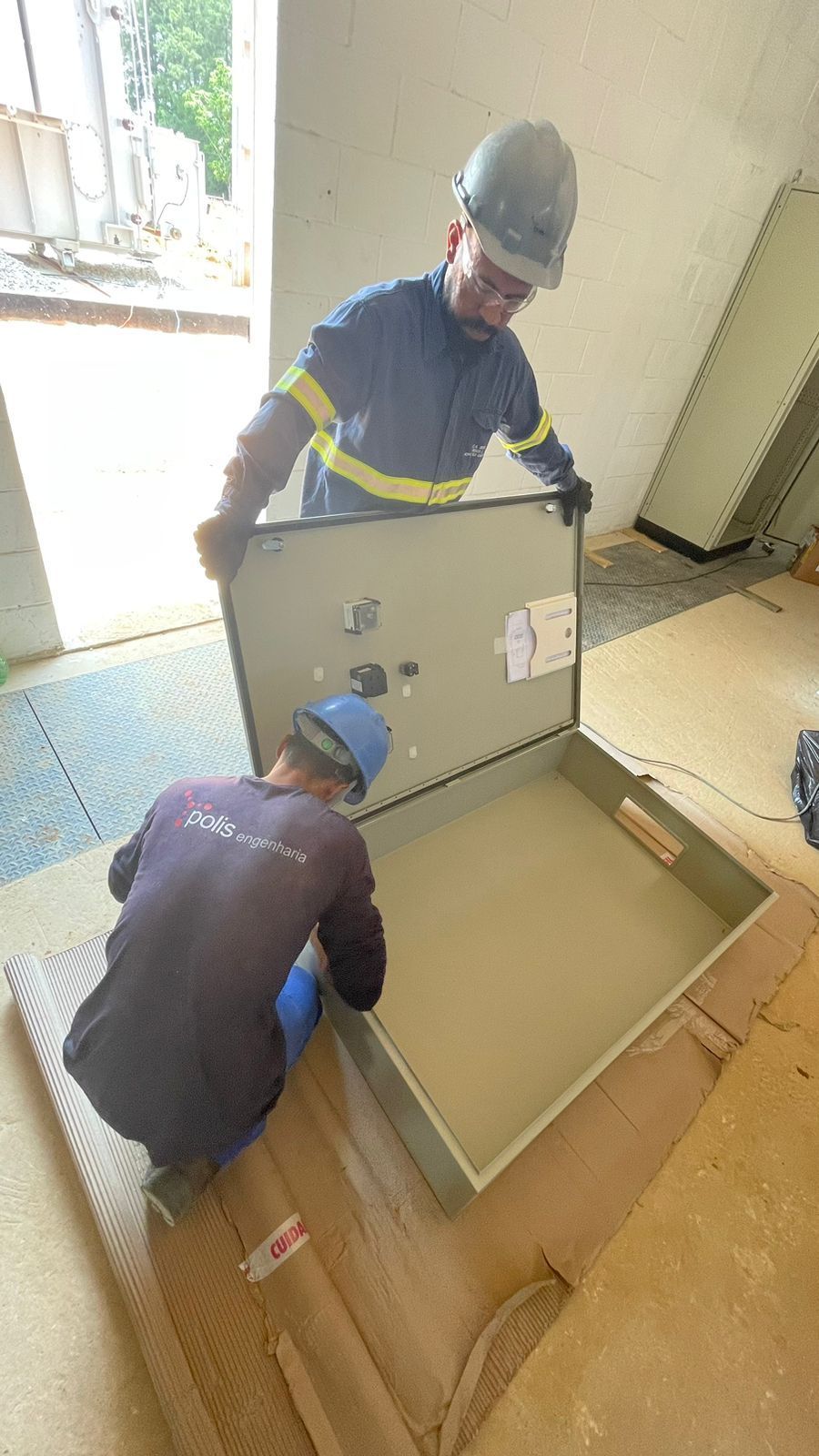 Dois homens estão trabalhando em uma caixa em uma sala.