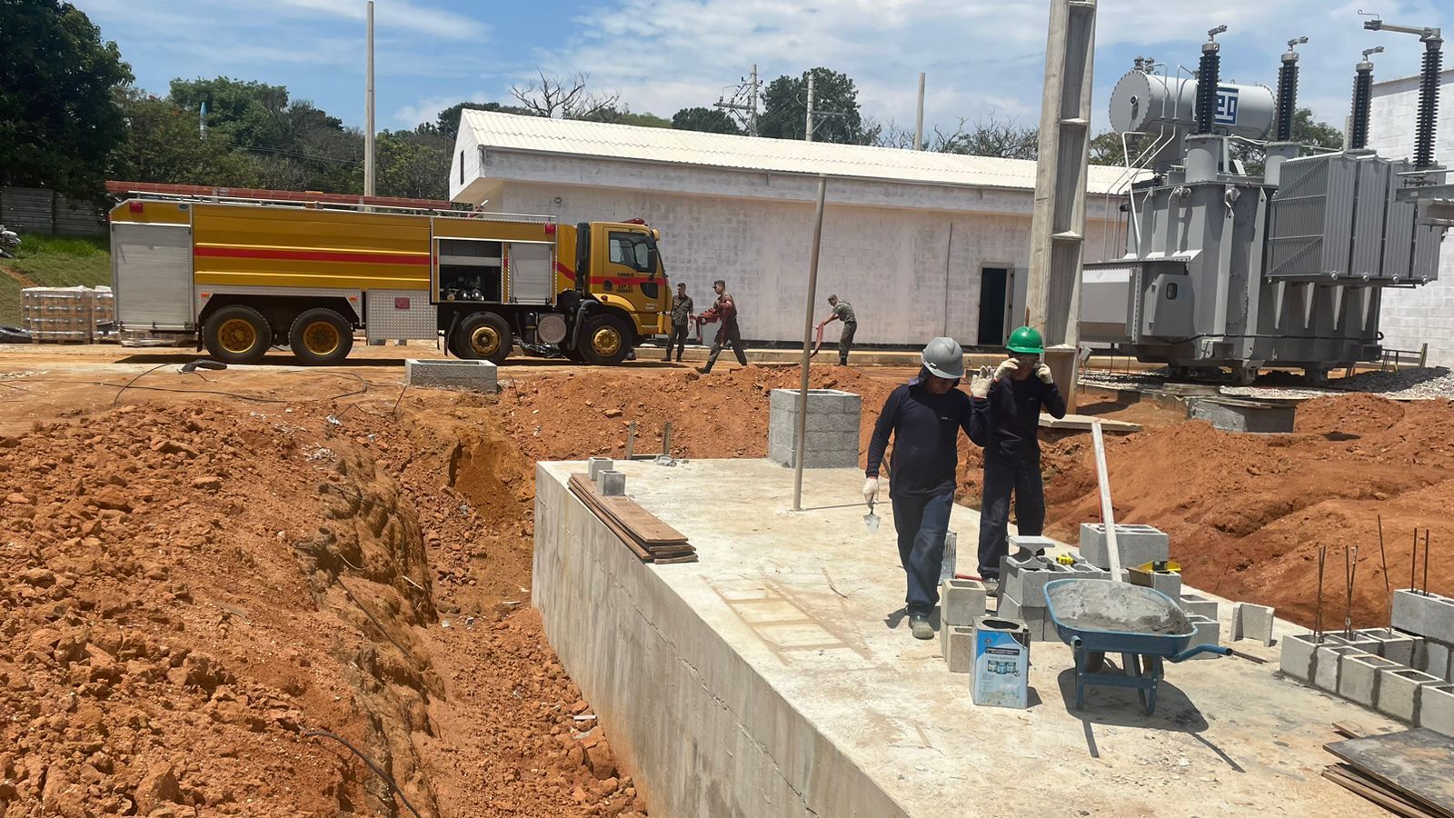 Um canteiro de obras com um caminhão de bombeiros ao fundo.