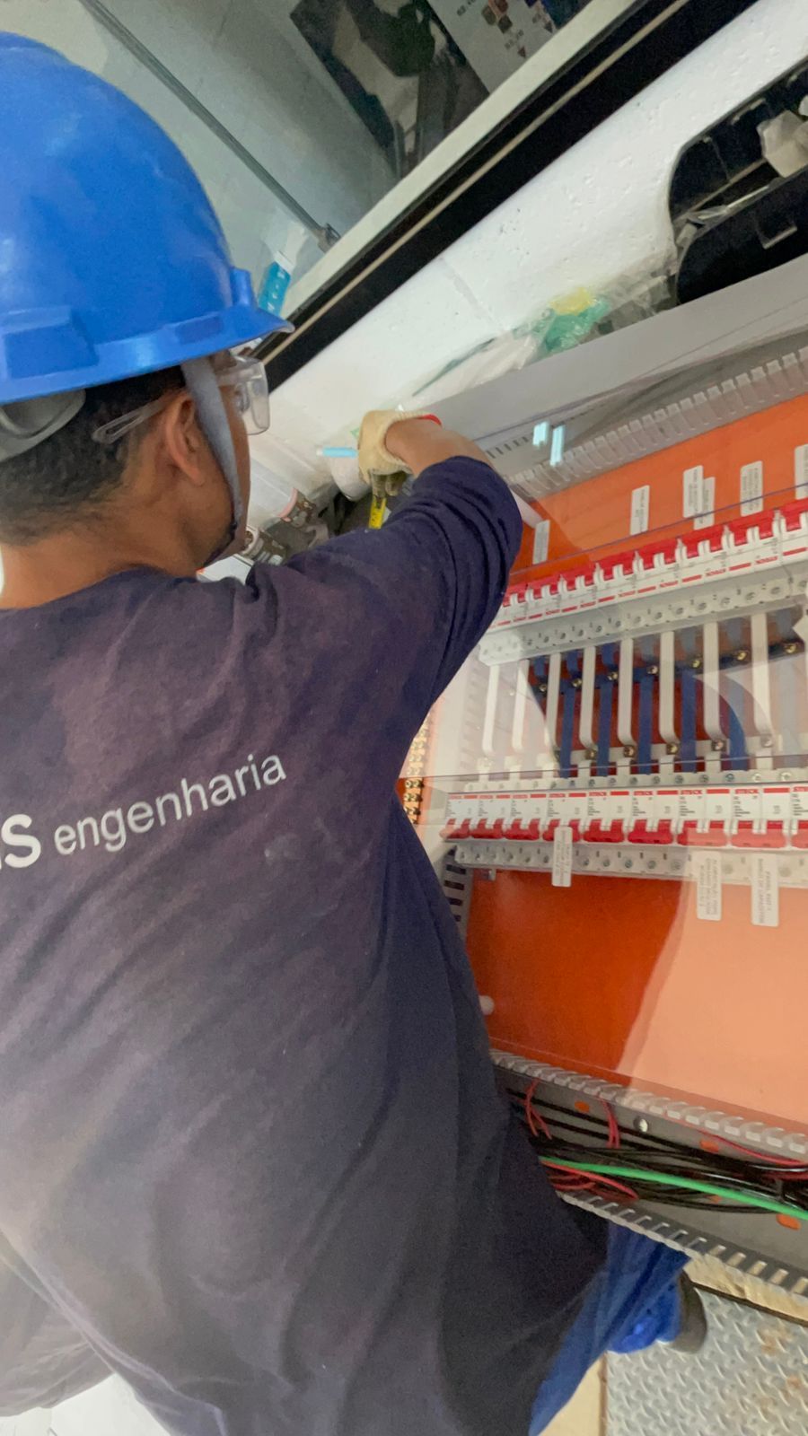 Um homem usando um capacete azul está trabalhando em uma máquina.