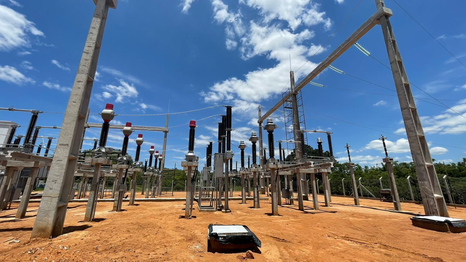 Uma fileira de linhas de energia sobre um campo de terra.