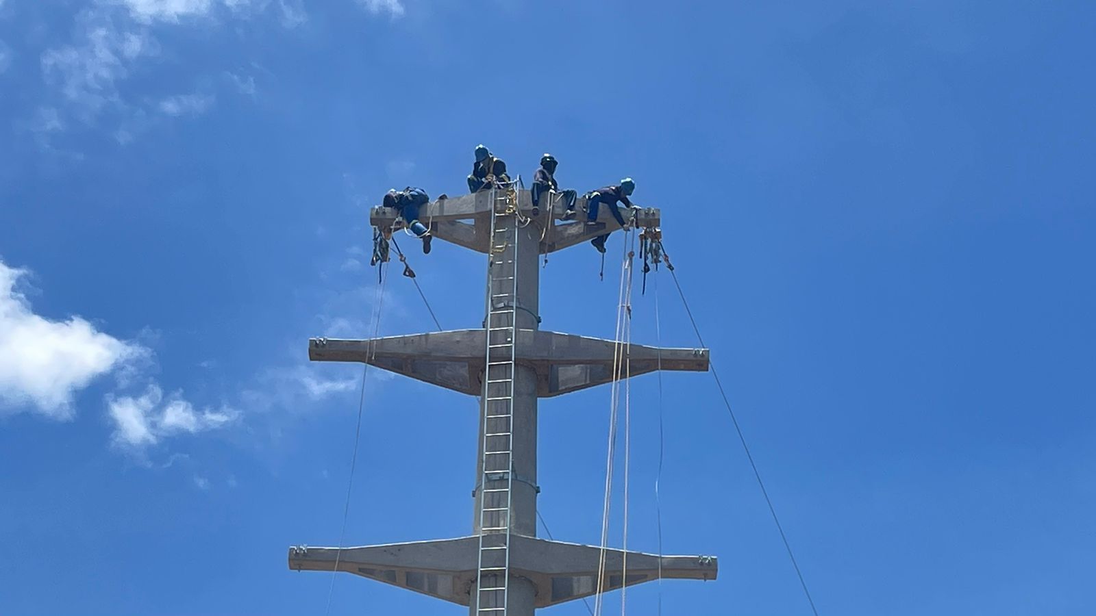 Um grupo de pessoas está em pé no topo de um poste telefônico.
