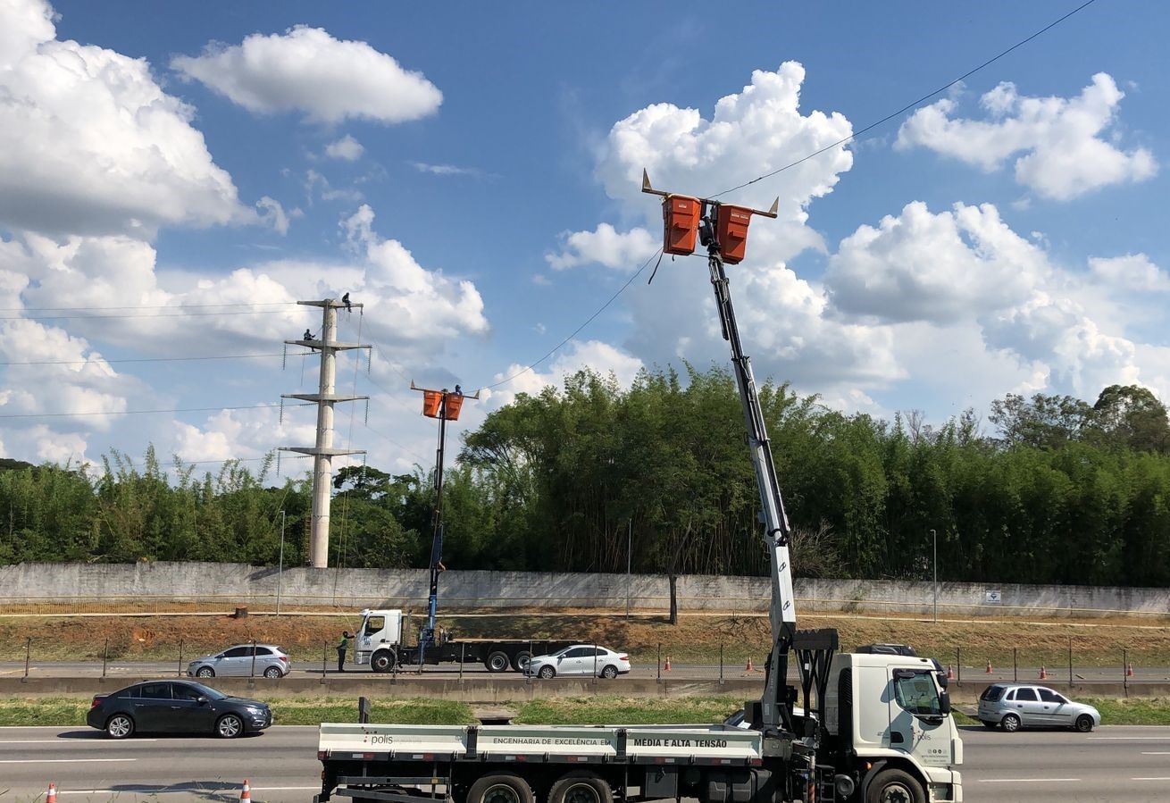 Um caminhão está trafegando por uma rodovia com um guindaste preso na traseira.