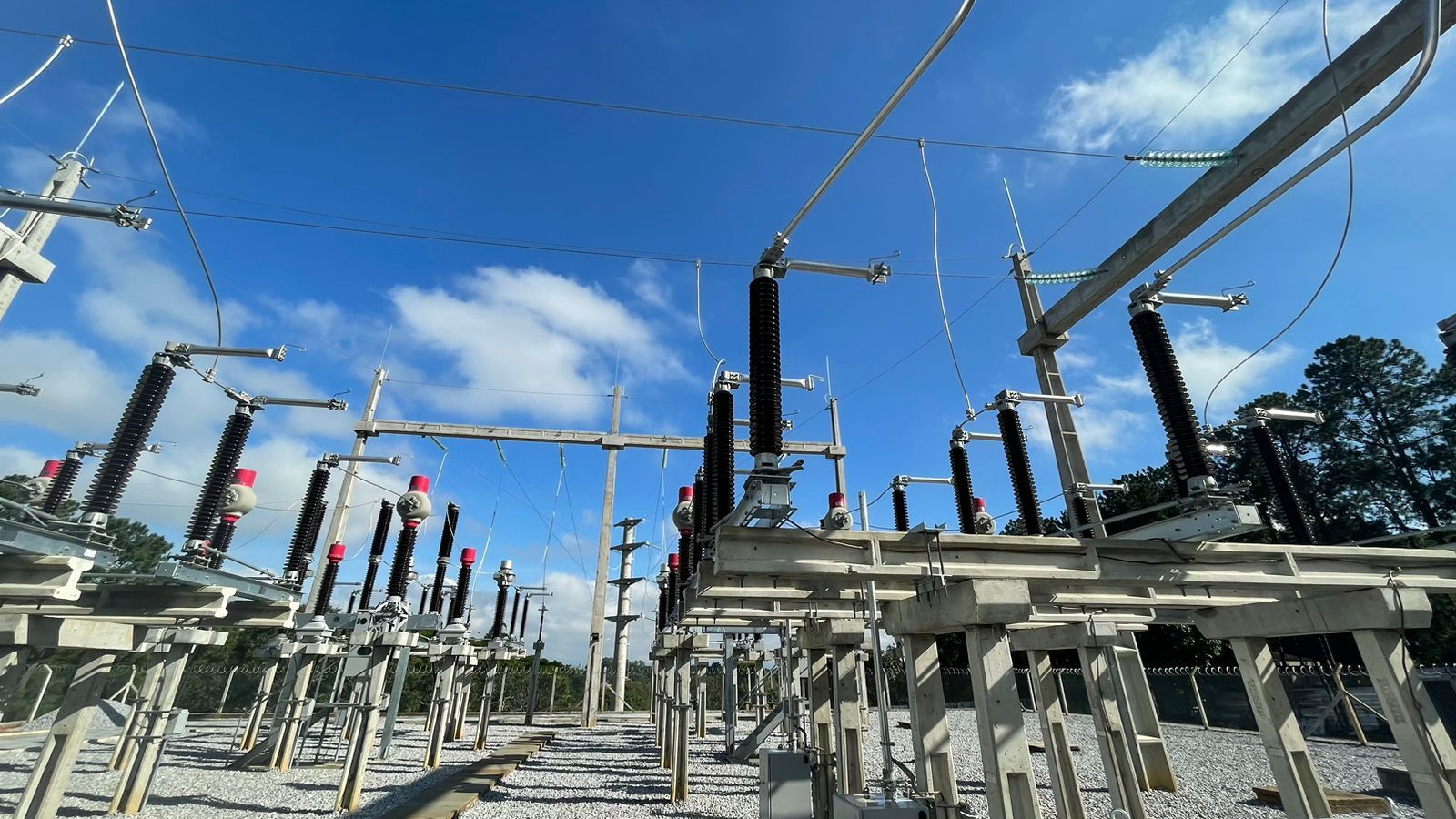 Uma grande subestação elétrica com um céu azul ao fundo.