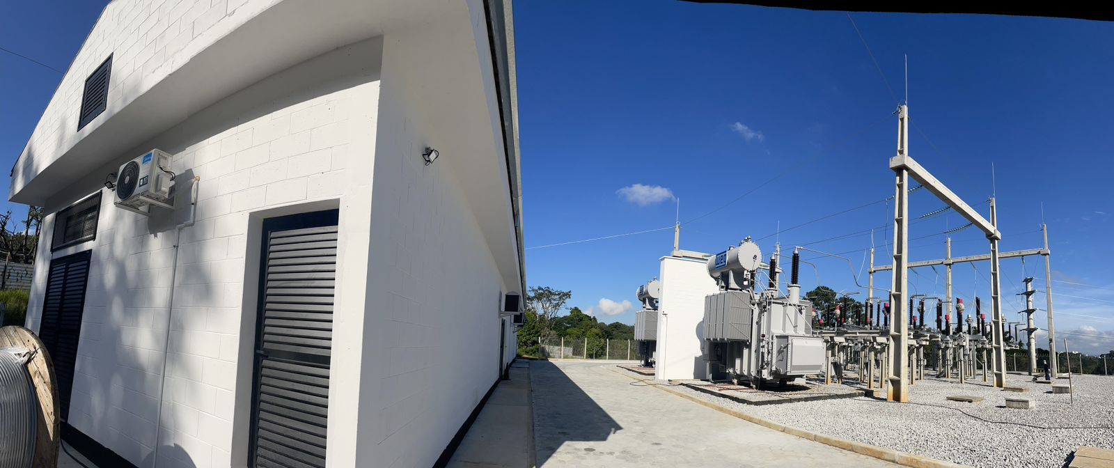 Um prédio branco e uma usina elétrica com um céu azul ao fundo.