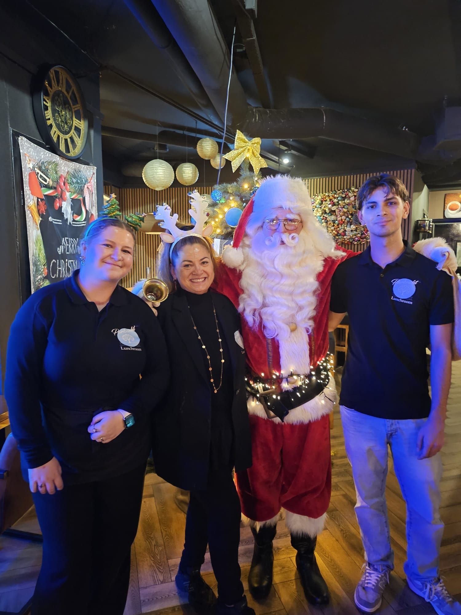 Een groep mensen poseert met de kerstman in een bar die versierd is voor Kerstmis.
