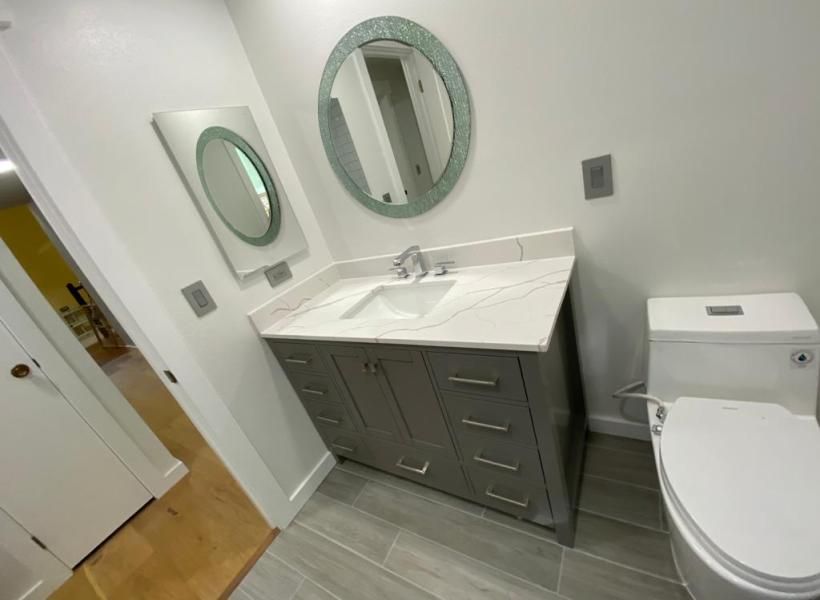 A bathroom with a sink , toilet and two mirrors.