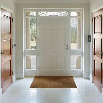A hallway with a white door and brown doors leading to it.