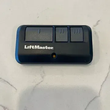 A liftmaster garage door remote control is sitting on top of a marble counter.