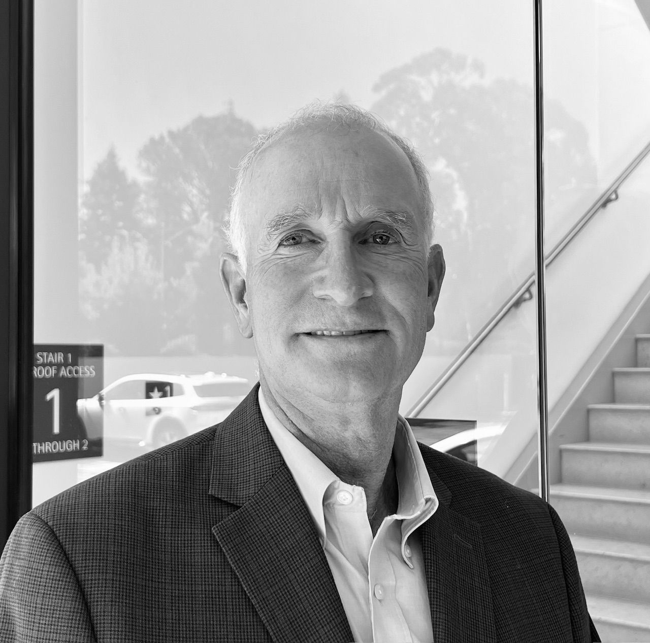 A man in a suit is standing in front of stairs and a sign that says 1
