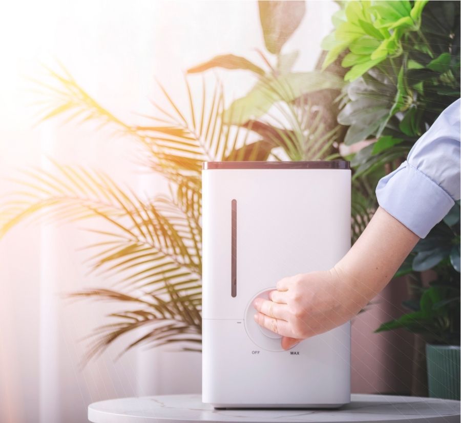 A person is pressing a button on a white humidifier