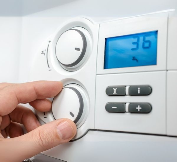 A person is adjusting a thermostat with the number 36 on the screen