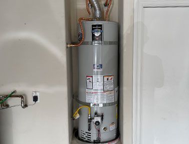 A water heater is sitting in a corner of a room.