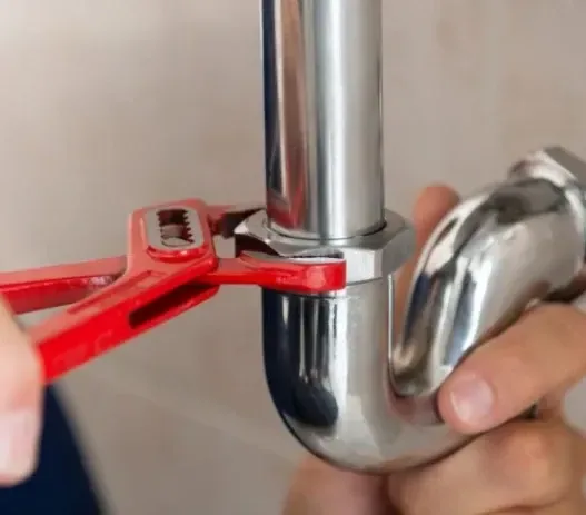 A person is fixing a pipe with a wrench.