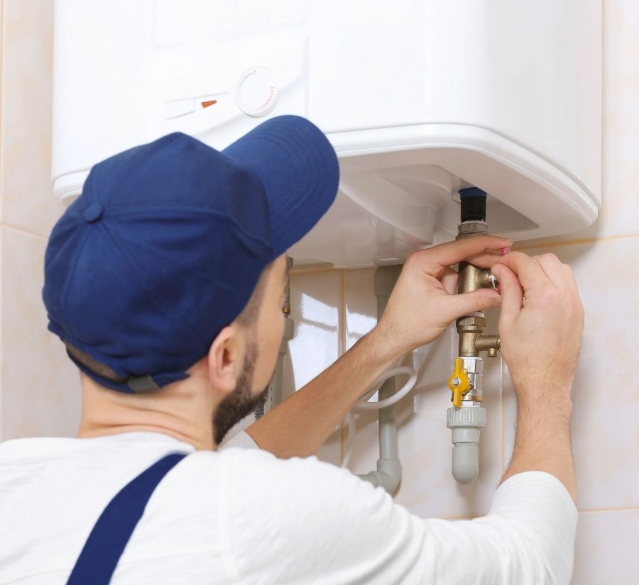 A man in a blue hat is fixing a water heater
