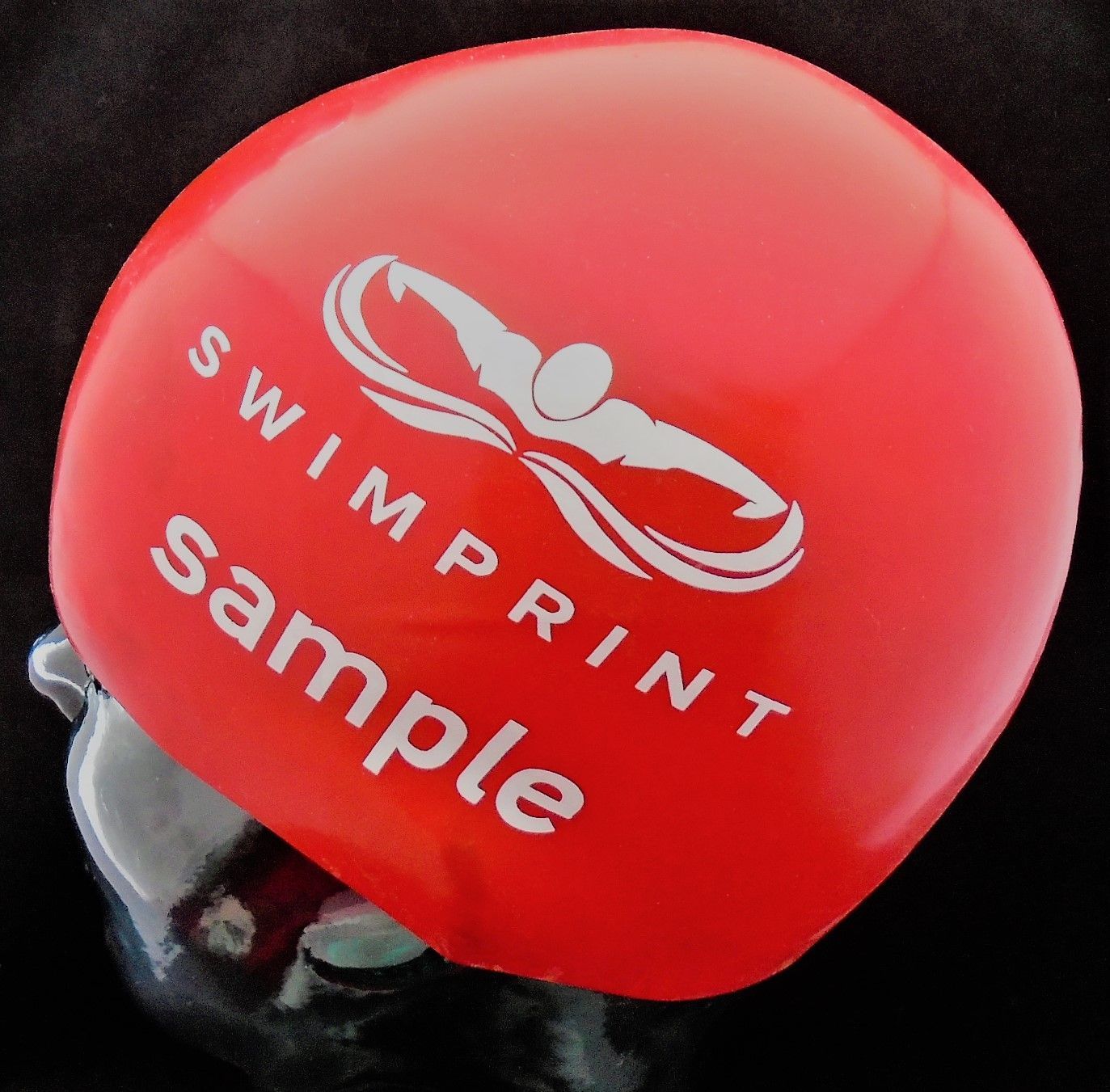 Eine rote Badekappe mit der Aufschrift „Swimprint Sample“