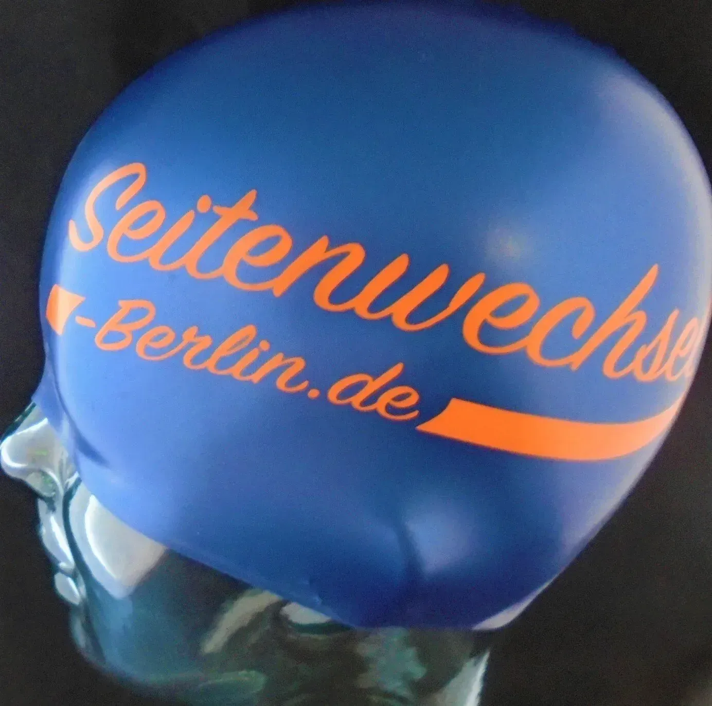 Eine blaue Badekappe mit der Aufschrift berlin.de