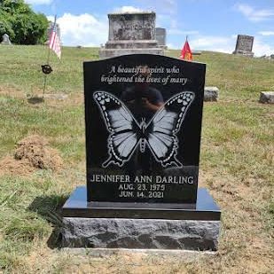 A black gravestone with a butterfly on it in a cemetery.