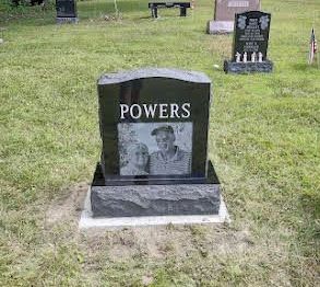 A black gravestone with a picture of a man and woman on it in a cemetery.