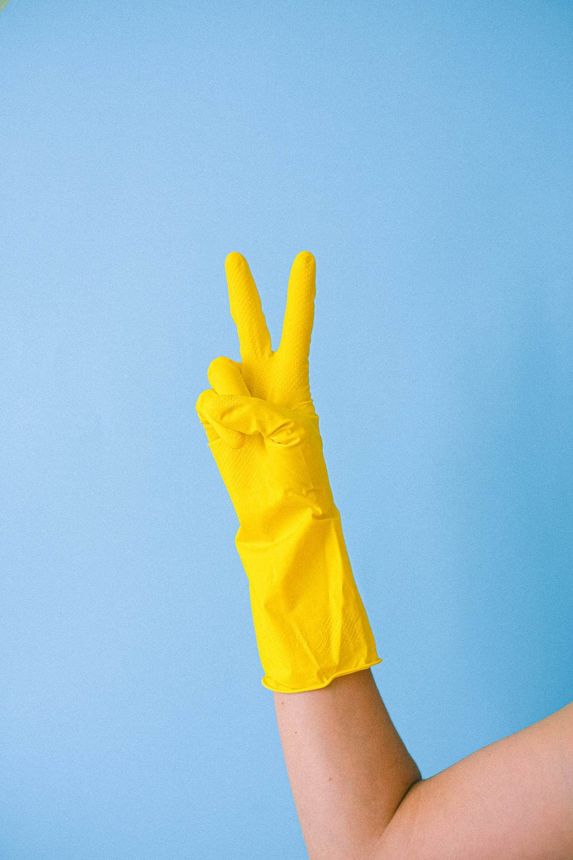 Cleaning services in Newmarket with yellow glove making peace sign blue background