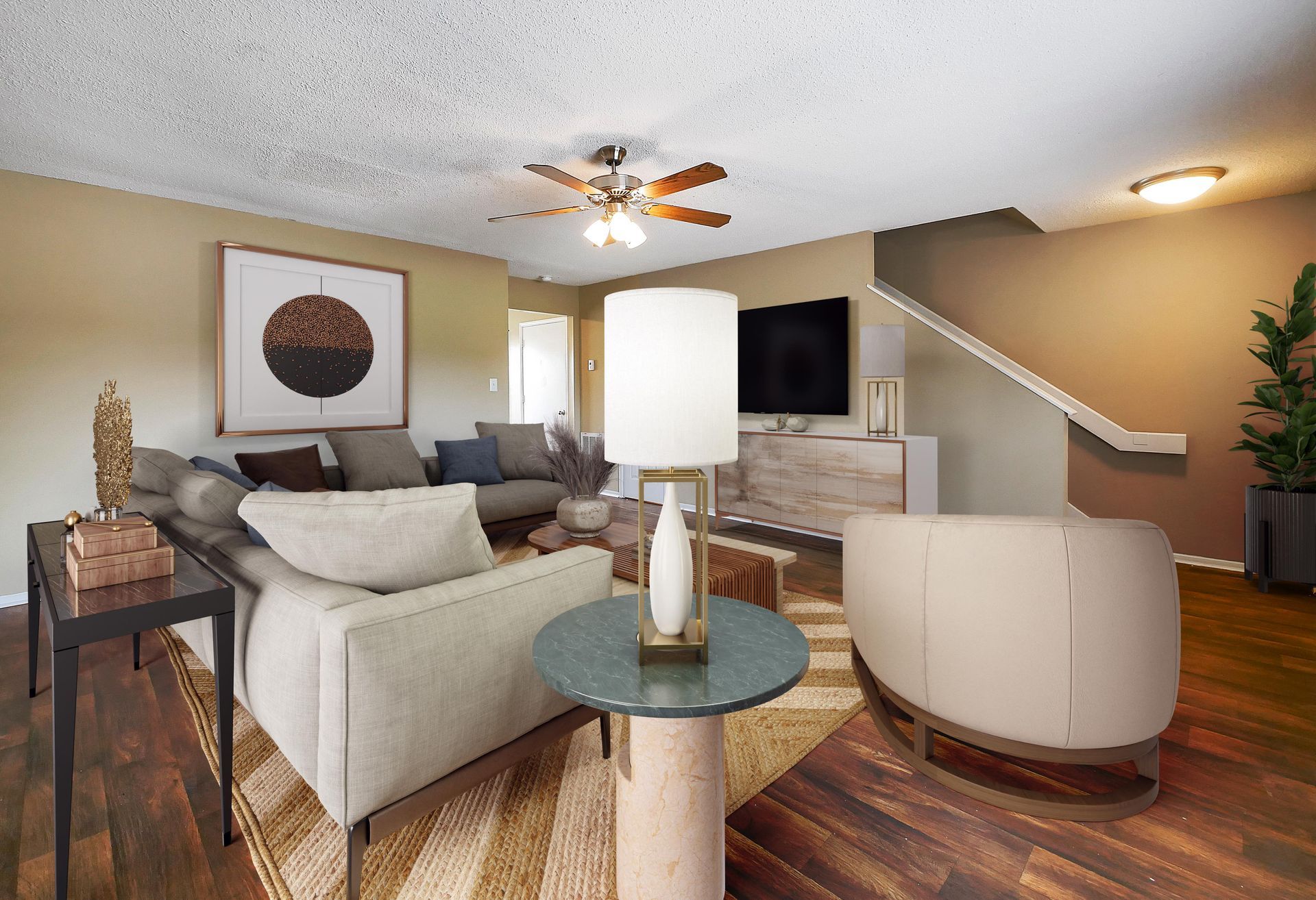 A modern living room with a neutral sectional sofa, a round side table, a beige chair, and a television on a wood stand.