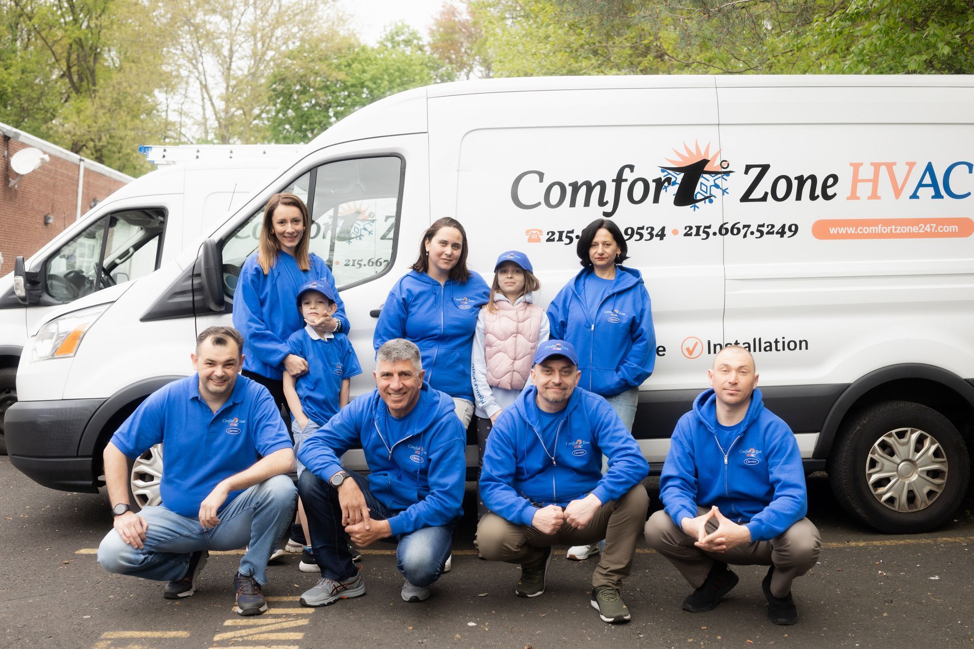 A group of people are posing for a picture in front of a comfort zone hvac van.