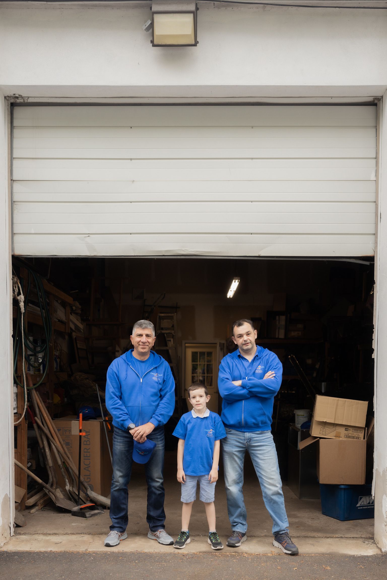 Three men and a boy are standing in front of a garage door.