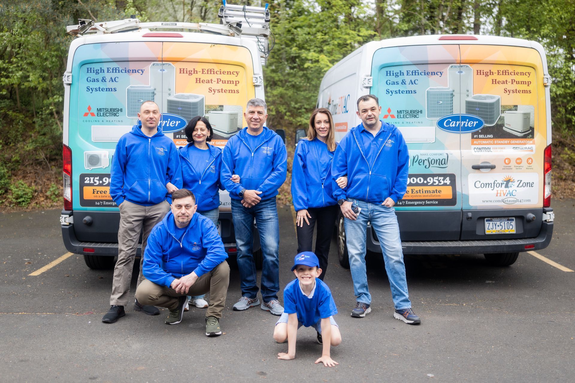 A group of people are posing for a picture in front of two vans.