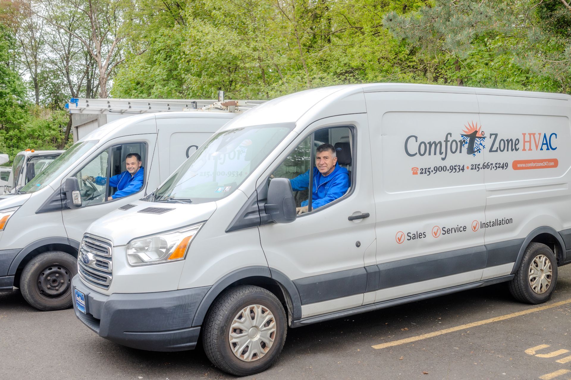 Two comfort zone hvac vans are parked next to each other in a parking lot.