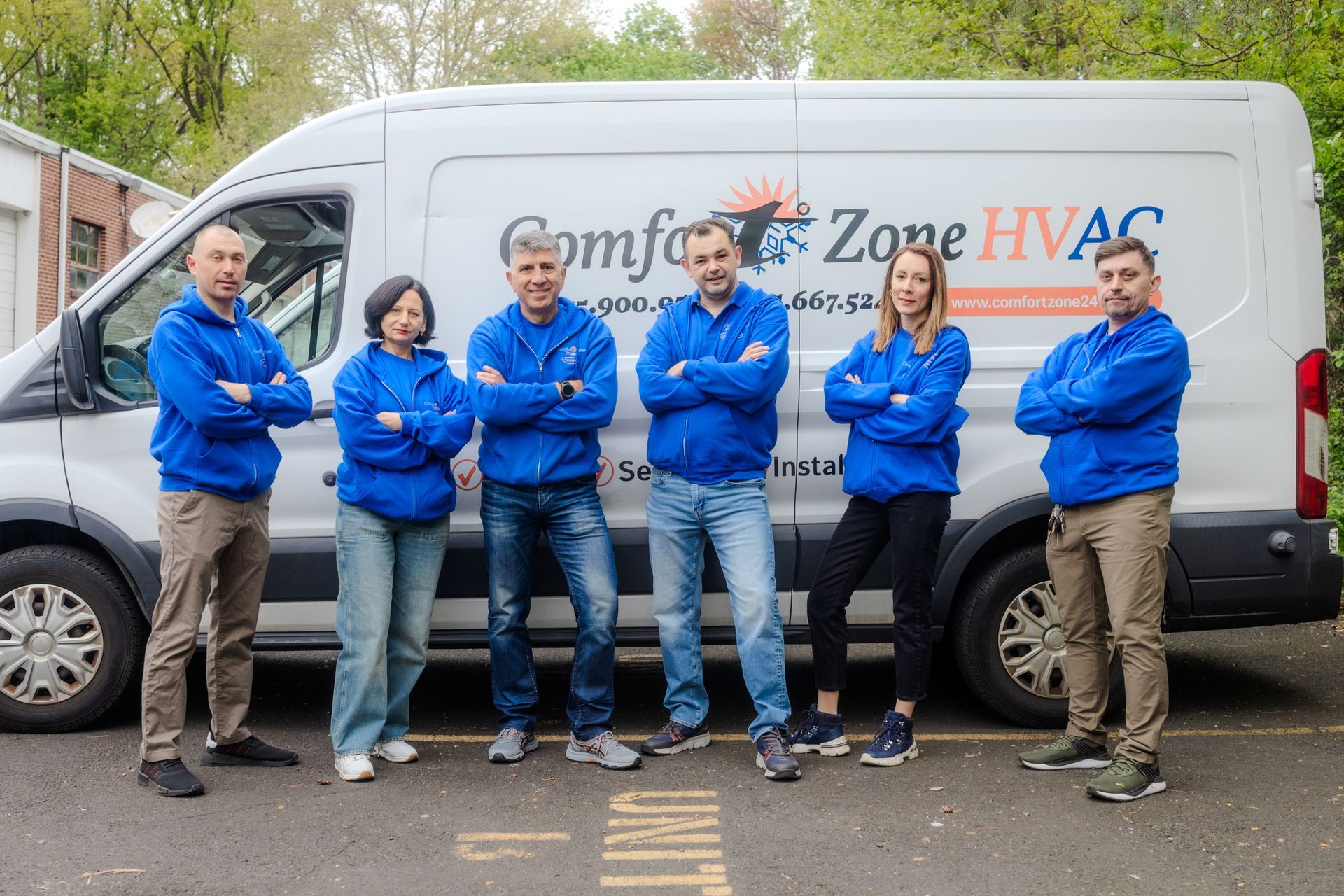 A group of people standing in front of a van that says comfort zone hvac