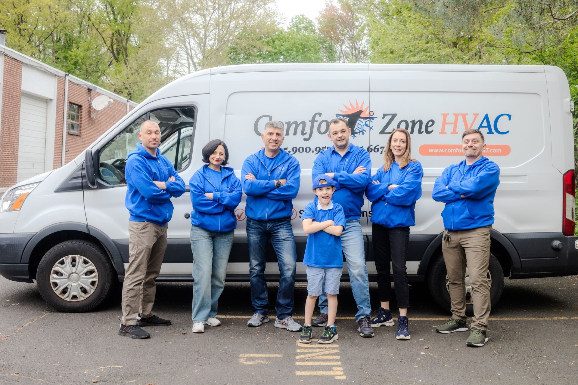 A group of people standing in front of a van that says comfort zone hvac.