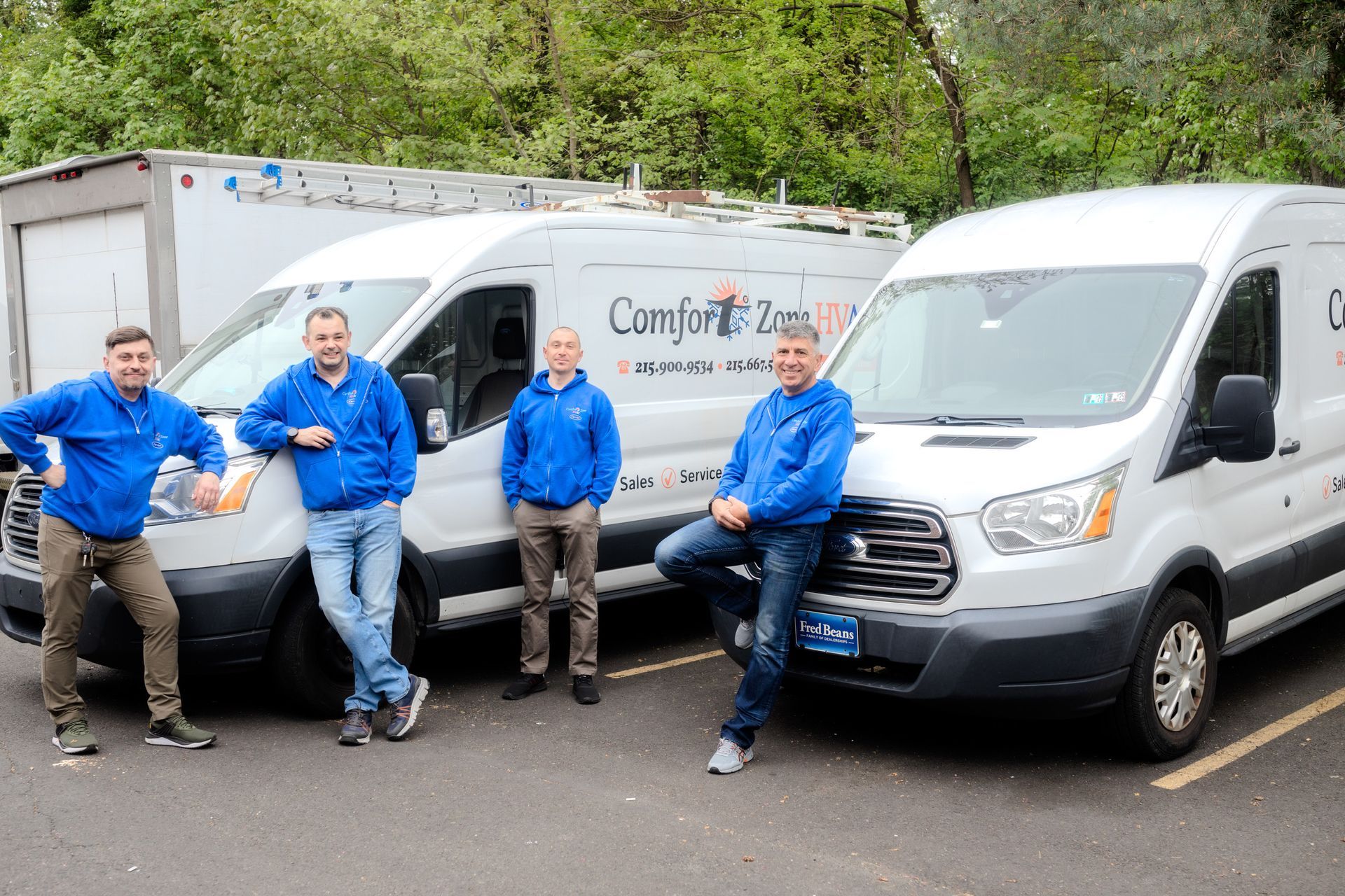 A group of men are posing for a picture in front of three vans.