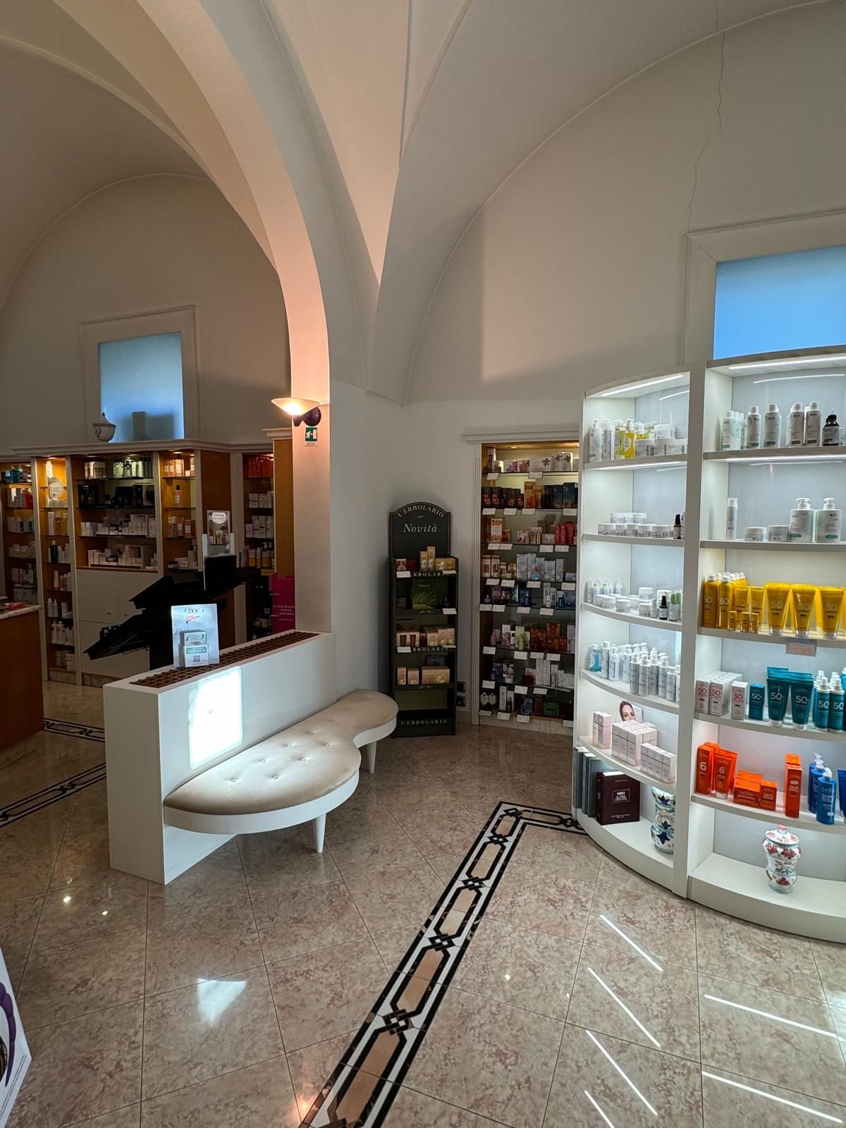 Una farmacia con molti scaffali e una panca al centro della stanza.