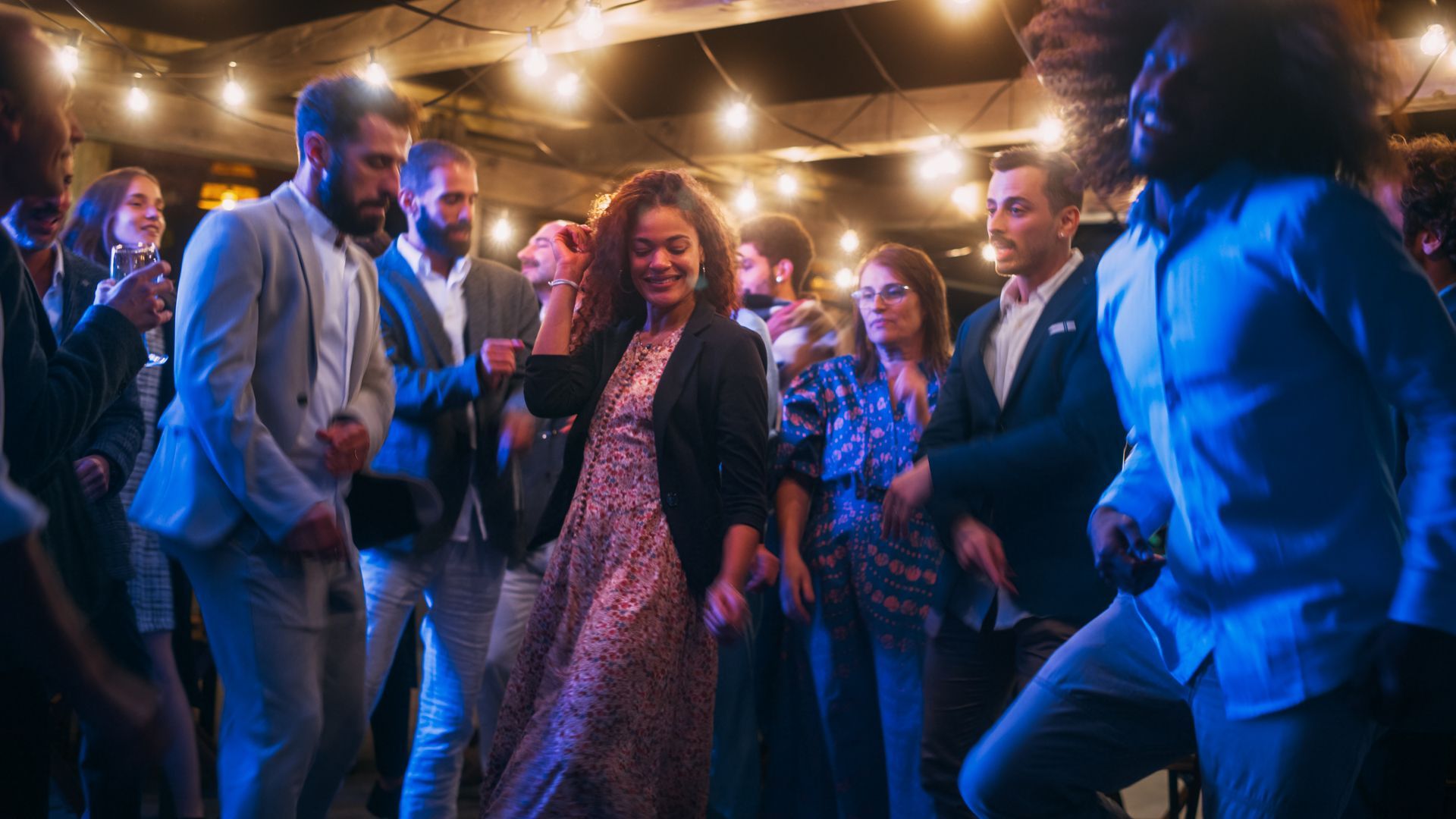 Group of people toasting drinks on a rooftop terrace, smiling and celebrating together.