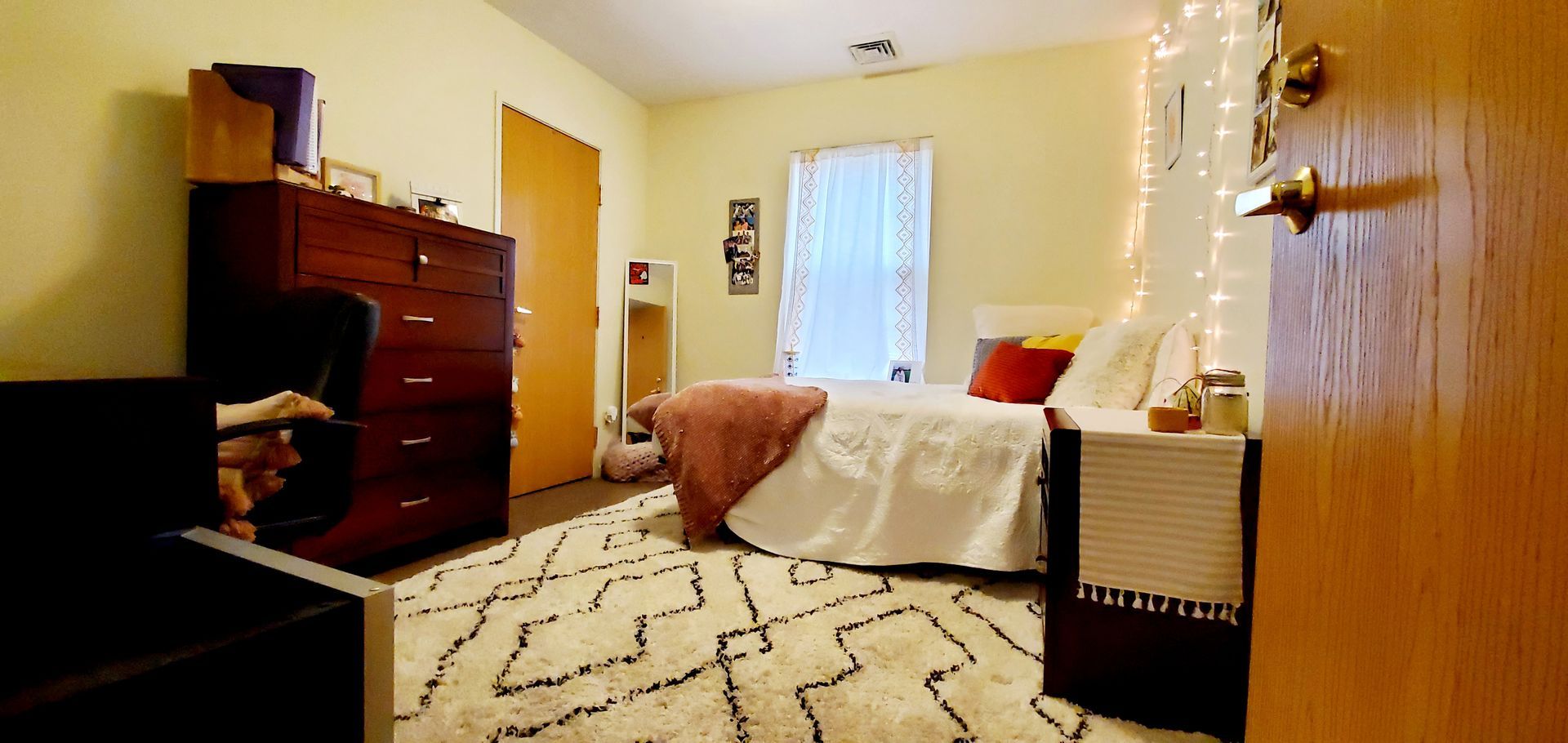 A bedroom with a bed , dresser , nightstand and rug.