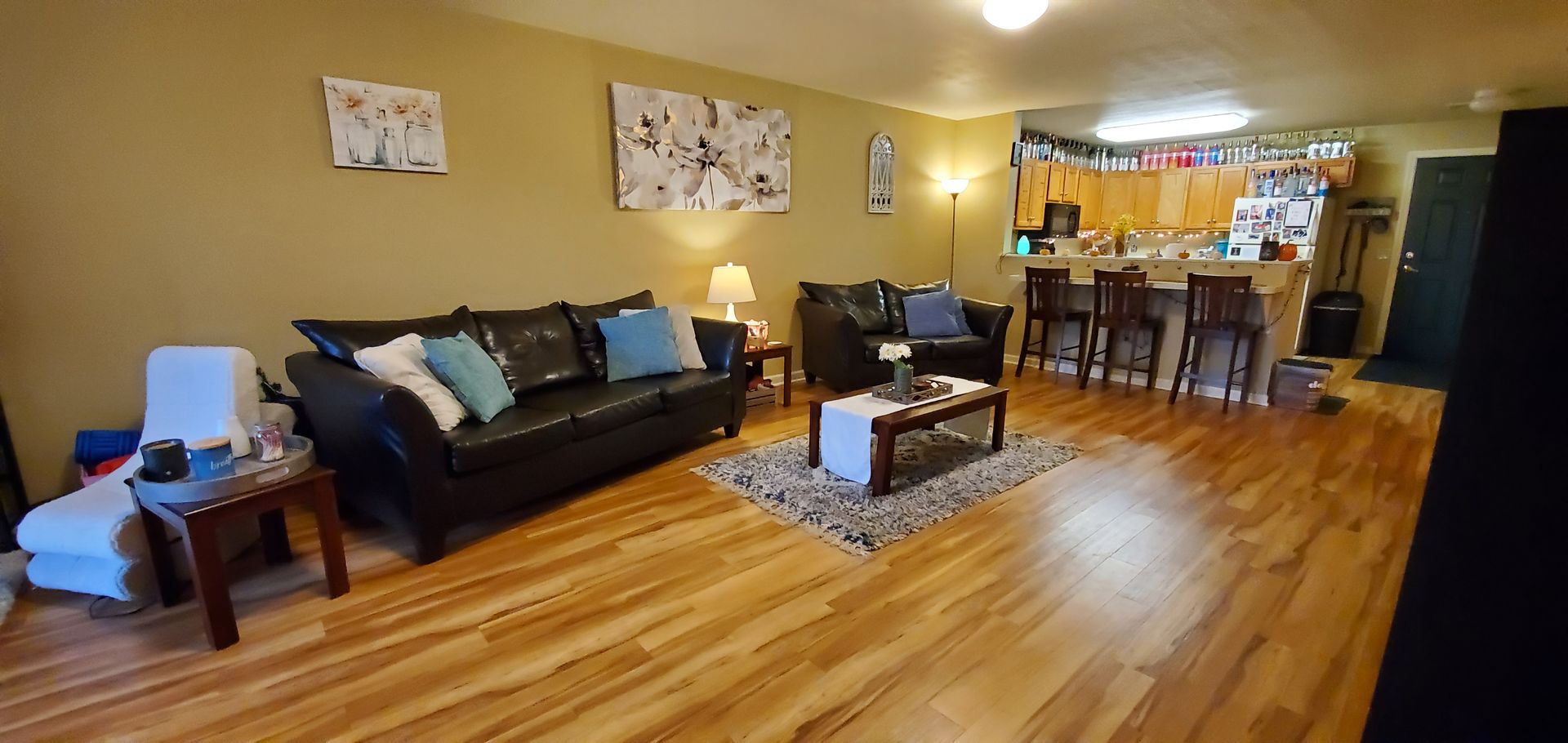 A living room with hardwood floors , a couch , chairs , and a coffee table.