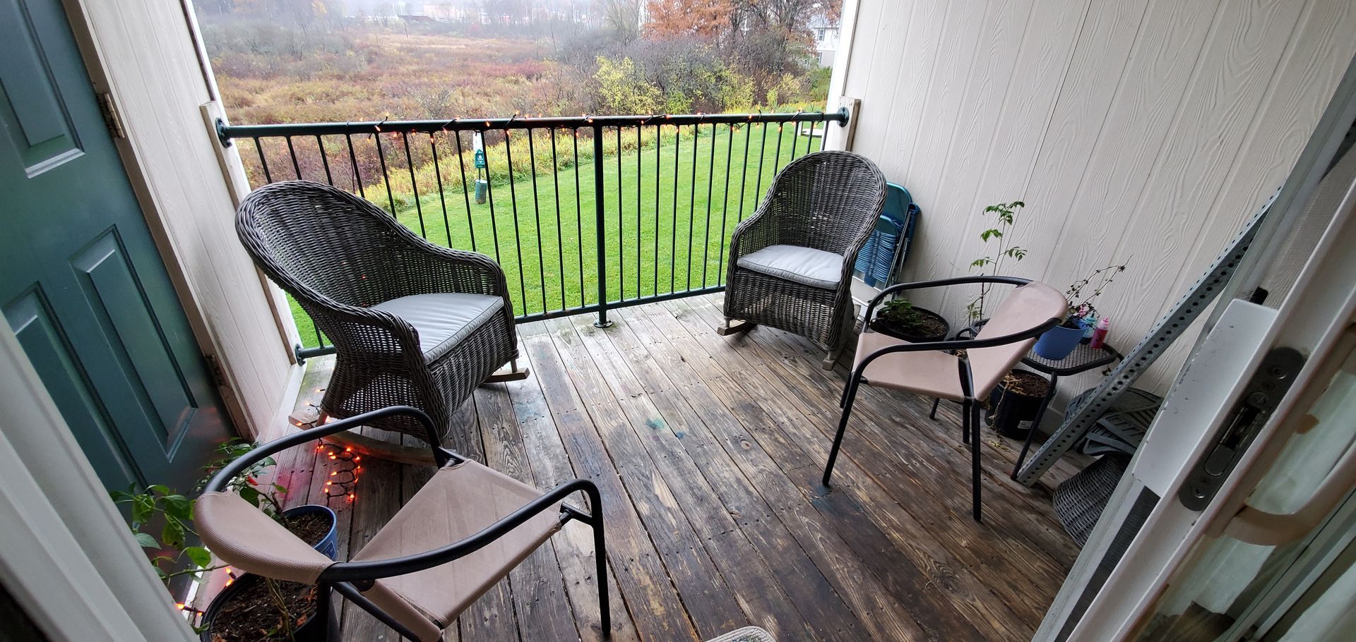 A balcony with wicker chairs , a table and a railing.